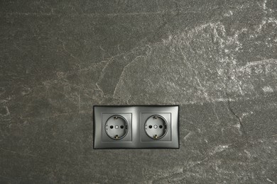 Power sockets on dark grey wall, space for text. Electrical supply