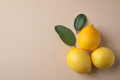 Ripe fresh lemon fruits and leaves on beige background, flat lay. Space for text