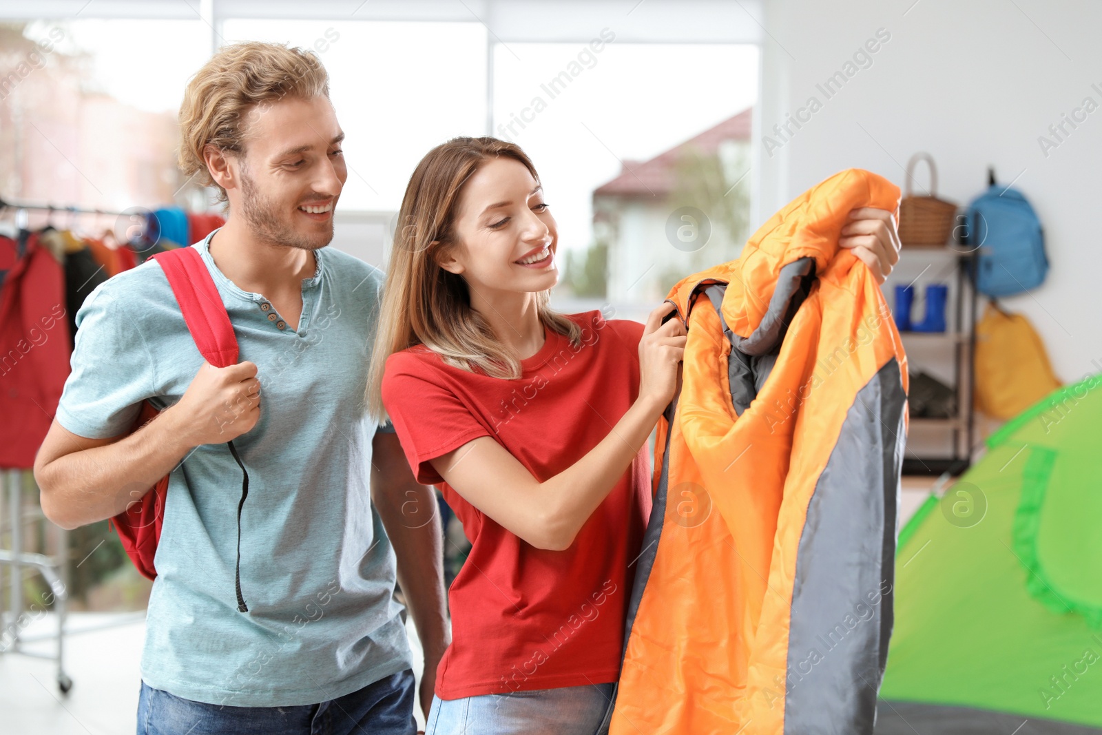 Photo of Young couple choosing sleeping bag in store
