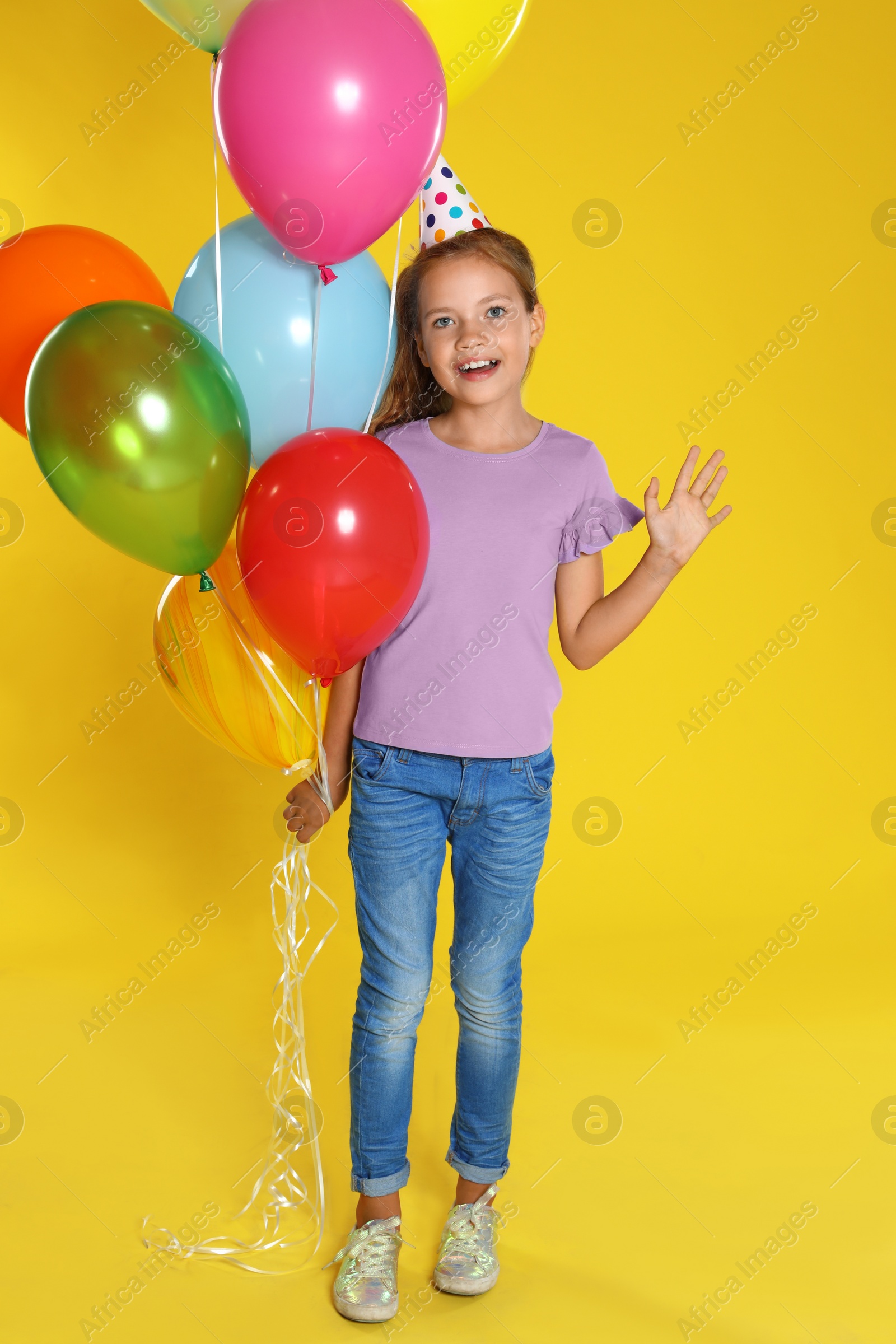 Photo of Happy girl with balloons on yellow background. Birthday celebration