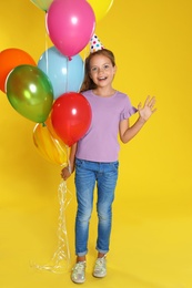 Happy girl with balloons on yellow background. Birthday celebration