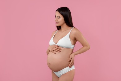 Beautiful pregnant woman in stylish comfortable underwear on pink background