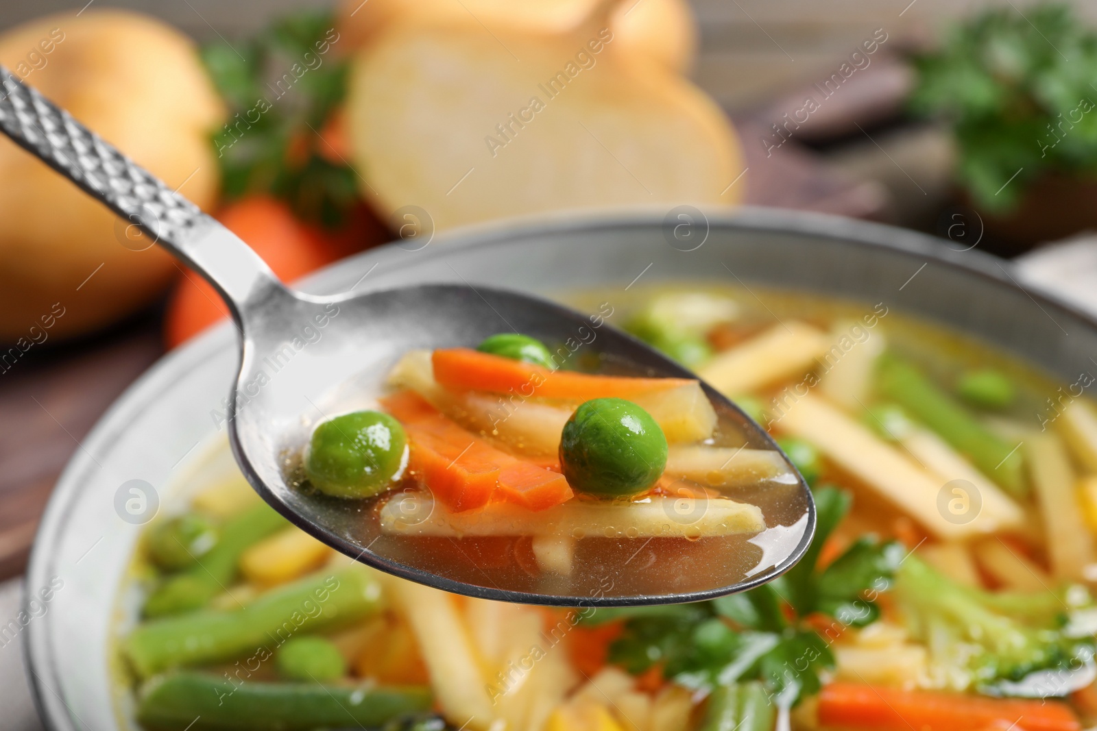 Photo of Spoon with delicious turnip soup above bowl, closeup