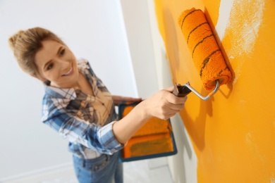 Photo of Happy woman painting wall indoors, above view. Home repair