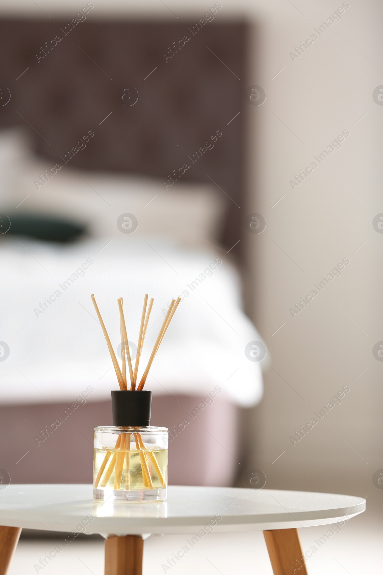 Photo of Aromatic reed air freshener on table against blurred background