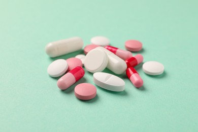 Photo of Pile of different pills on green background, selective focus