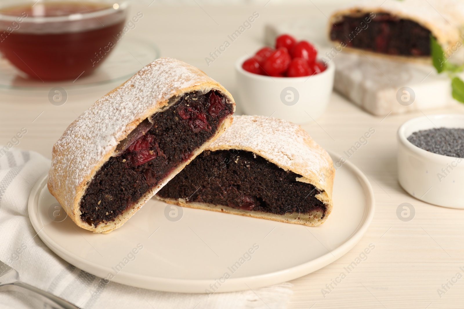 Photo of Delicious strudel with cherries and poppy seeds on white wooden table, closeup