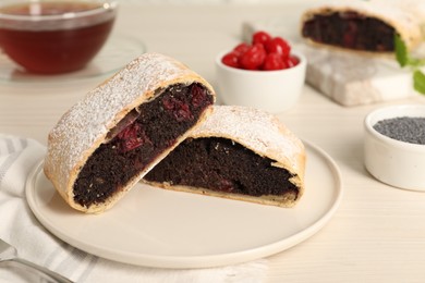 Delicious strudel with cherries and poppy seeds on white wooden table, closeup