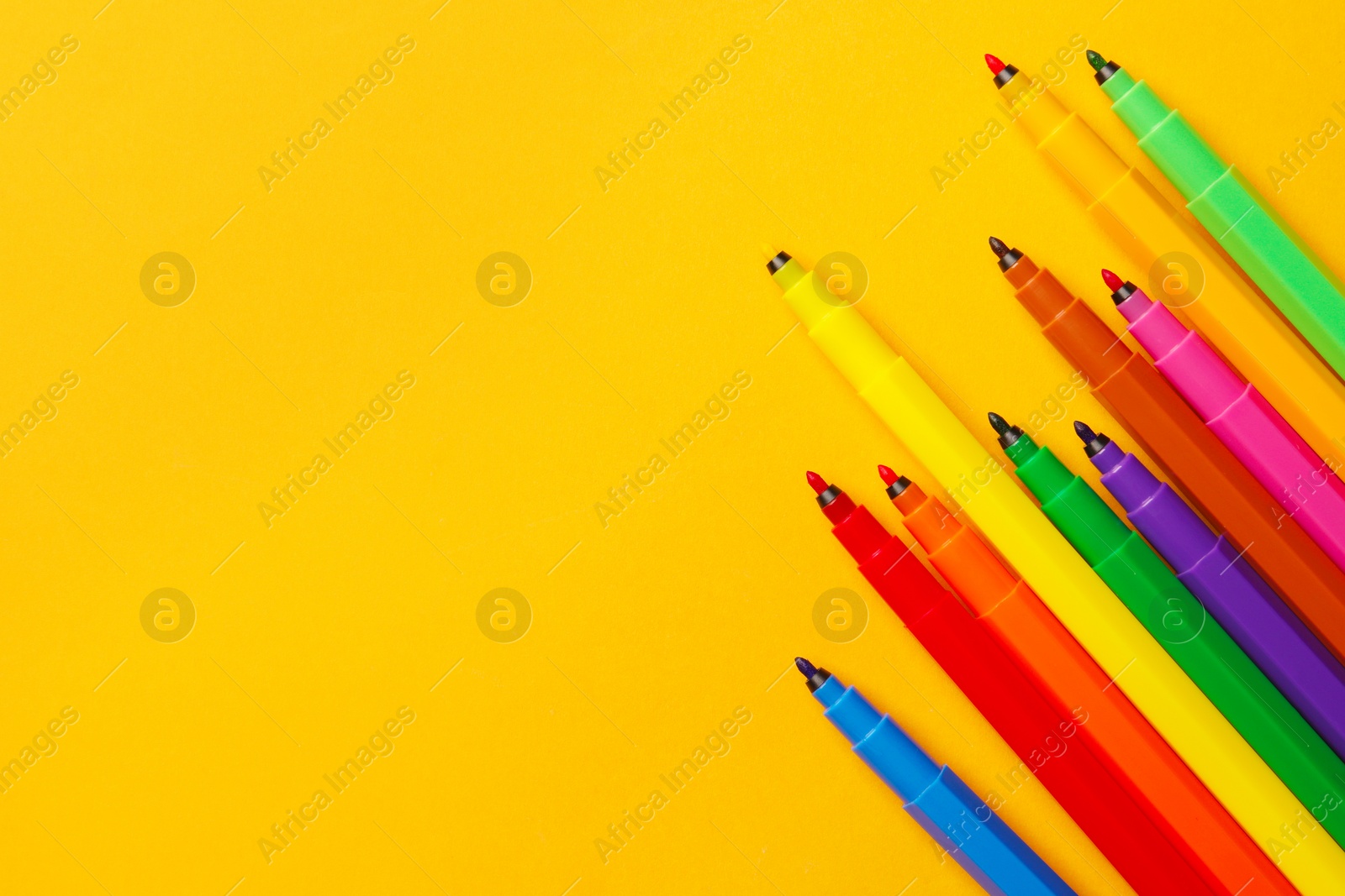 Photo of Many bright markers on yellow background, flat lay. Space for text