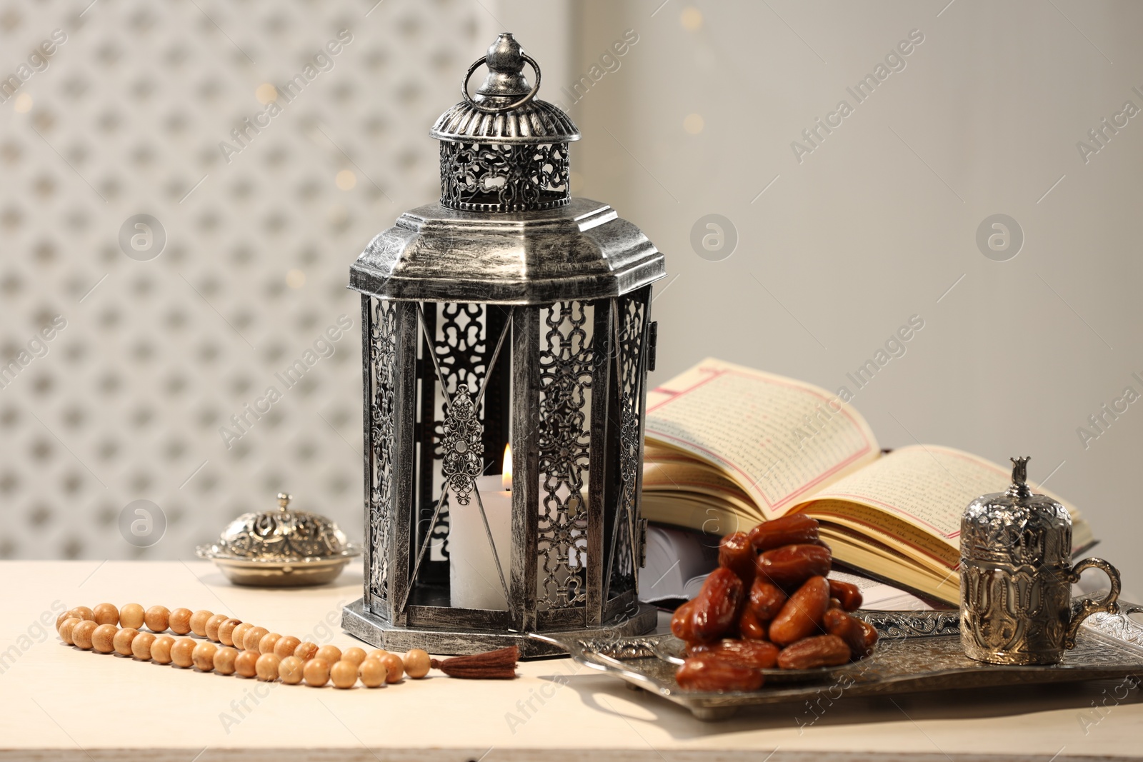 Photo of Arabic lantern, Quran, misbaha and dates on white table