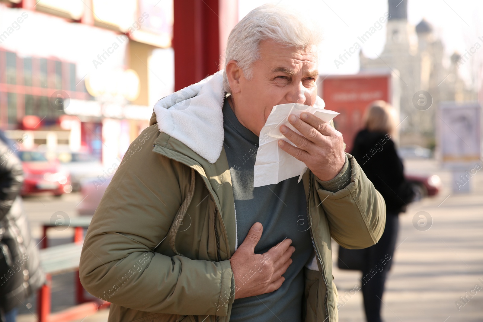 Photo of Sick senior man with tissue on city street. Influenza virus