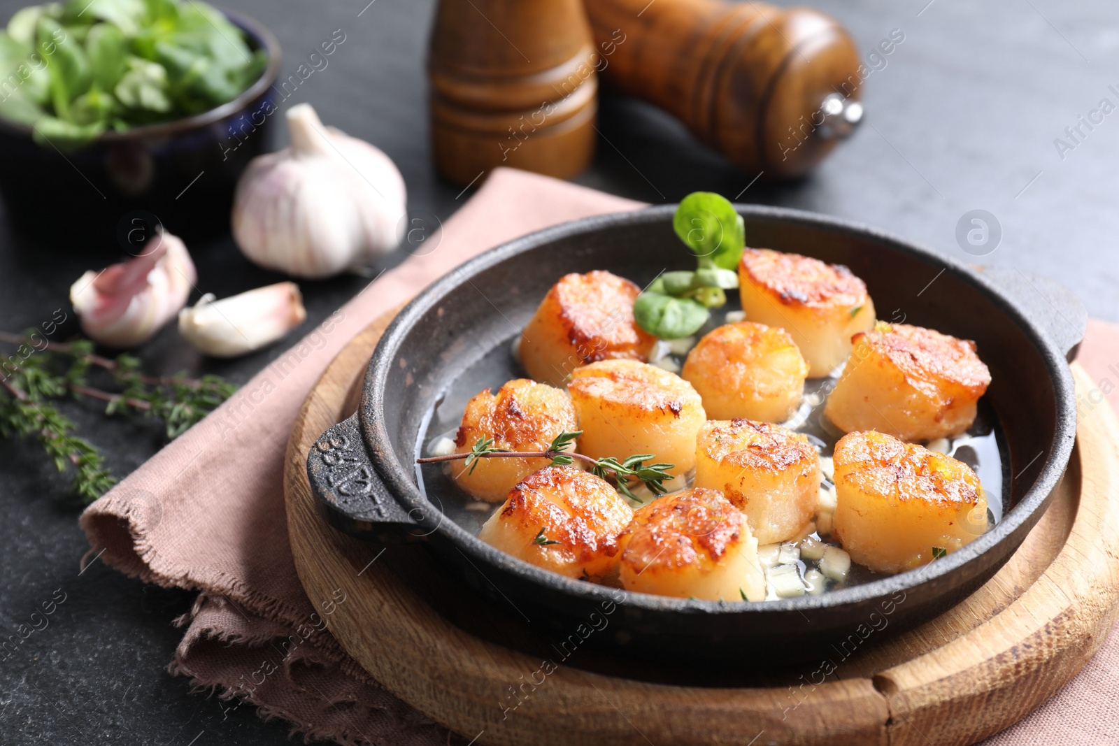 Photo of Delicious fried scallops and ingredients on dark gray textured table, closeup