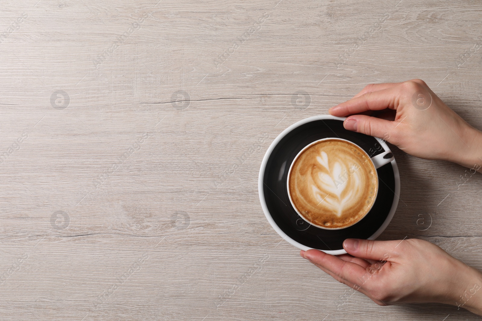 Photo of Woman with cup of aromatic coffee at wooden table, top view. Space for text