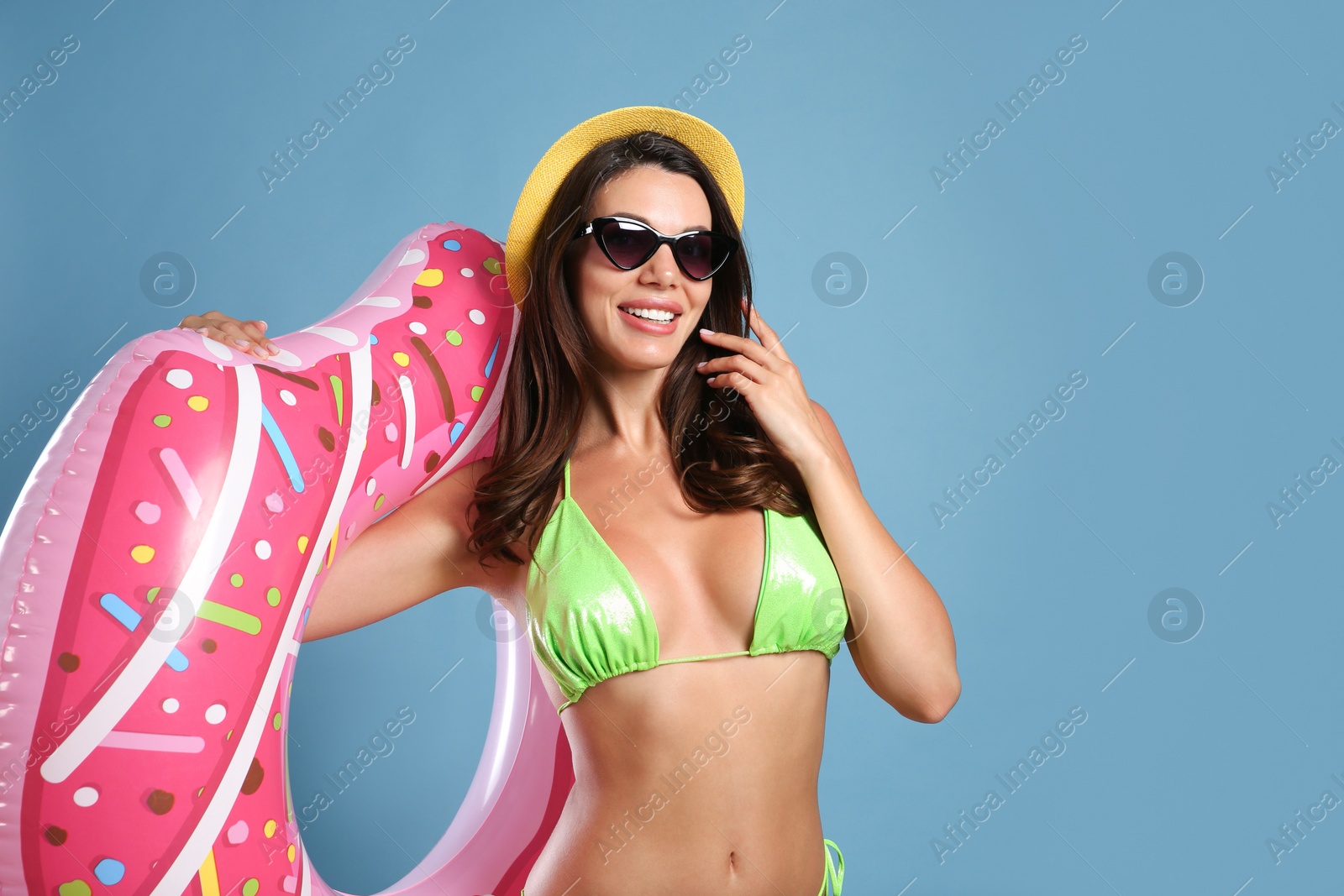 Photo of Beautiful woman in stylish bikini with inflatable ring on blue background. Space for text