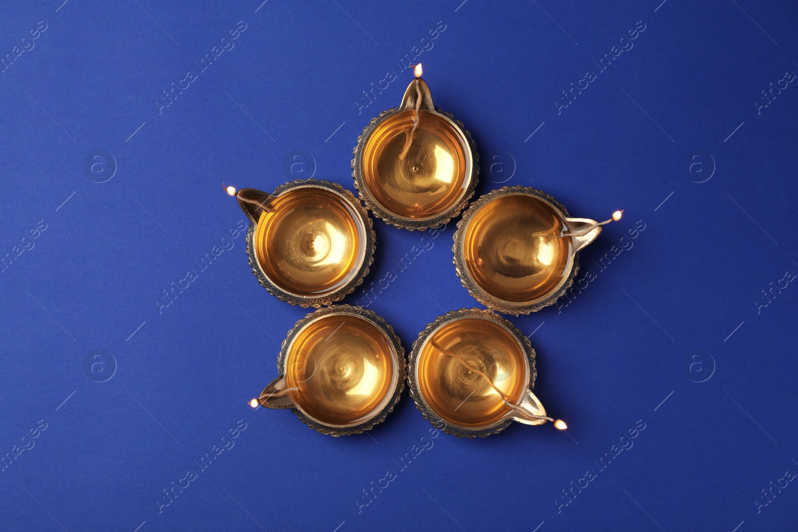 Photo of Diwali diyas or clay lamps on color background, top view