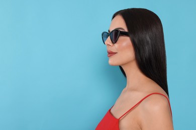 Photo of Attractive woman in fashionable sunglasses against light blue background. Space for text
