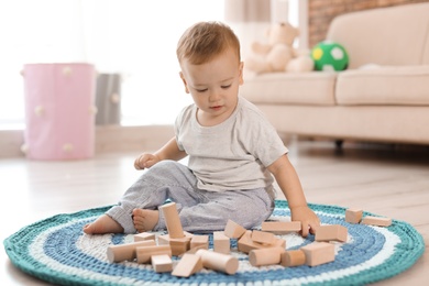 Photo of Adorable little baby playing with wooden blocks at home