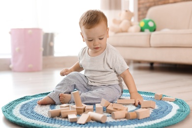 Adorable little baby playing with wooden blocks at home