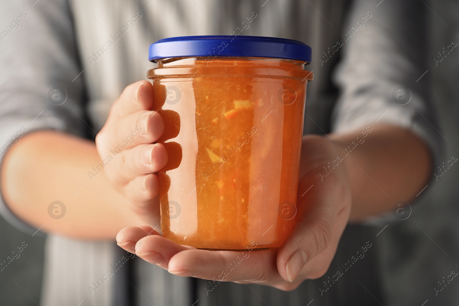 Photo of Woman with jar of orange jam, closeup