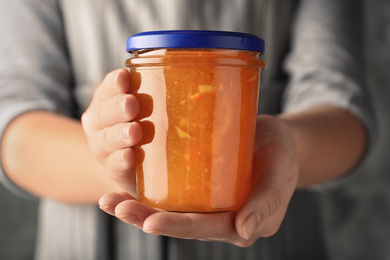 Photo of Woman with jar of orange jam, closeup