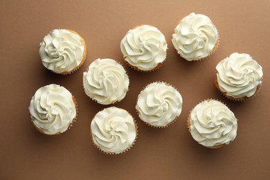 Tasty vanilla cupcakes with cream on dark beige background, top view