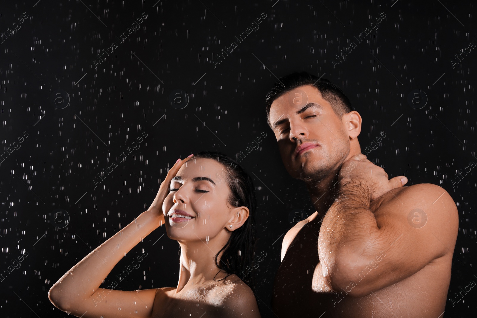 Photo of Couple taking shower against black background. Woman washing hair