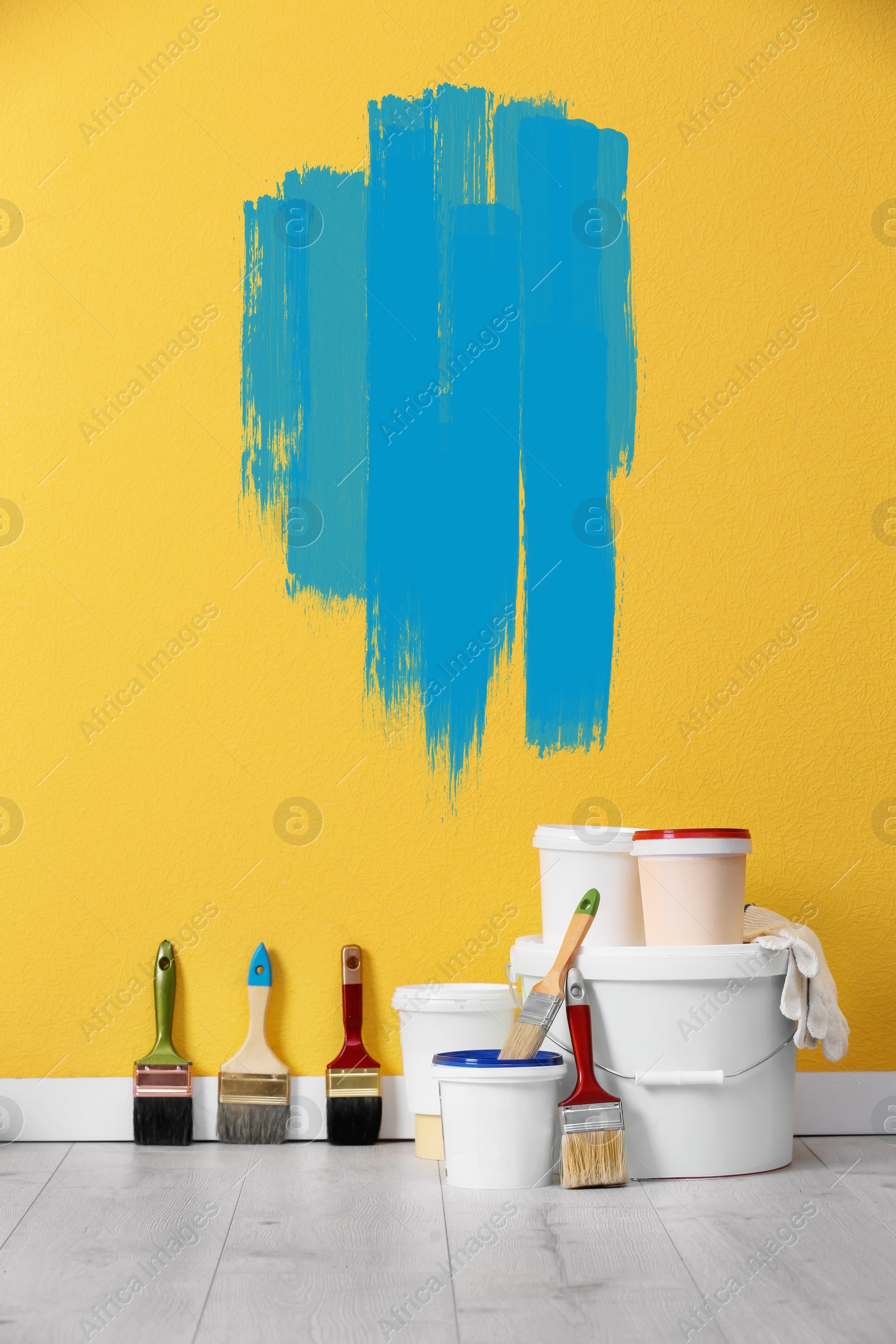 Image of Set with decorator's tools and paint on floor near yellow wall