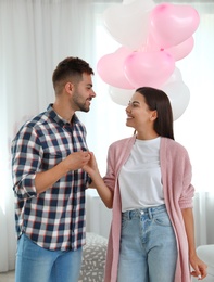 Photo of Young couple with air balloons at home. Celebration of Saint Valentine's Day