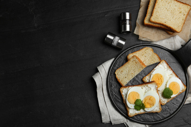Photo of Tasty sandwiches with boiled eggs served on black table, flat lay. Space for text