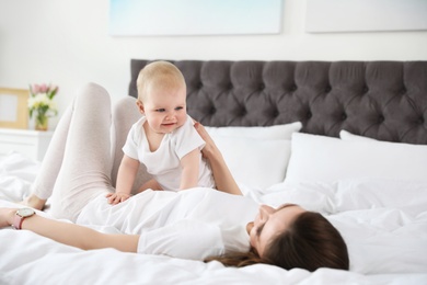 Happy mother with little baby on bed at home. Crawling time