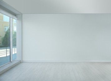 Photo of Empty room with large window and laminated floor