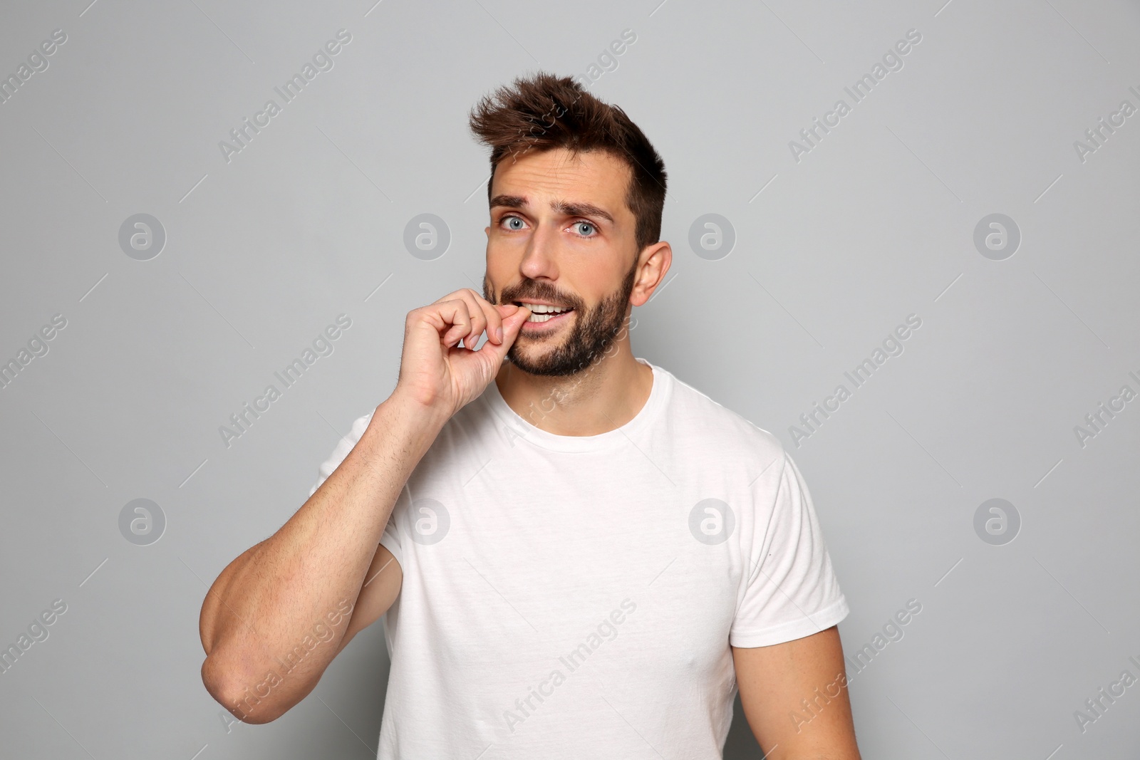 Photo of Man biting his nails on grey background