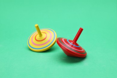Photo of Two bright spinning tops on green background. Toy whirligig