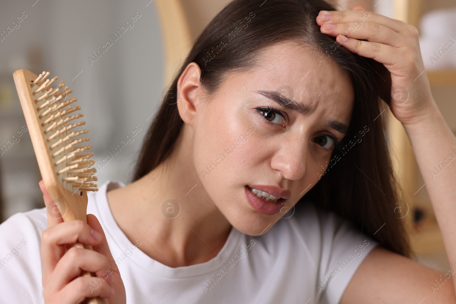Photo of Emotional woman with brush examining her hair on blurred background. Dandruff problem