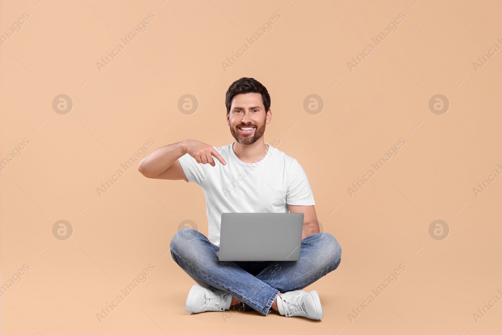 Photo of Happy man with laptop on beige background