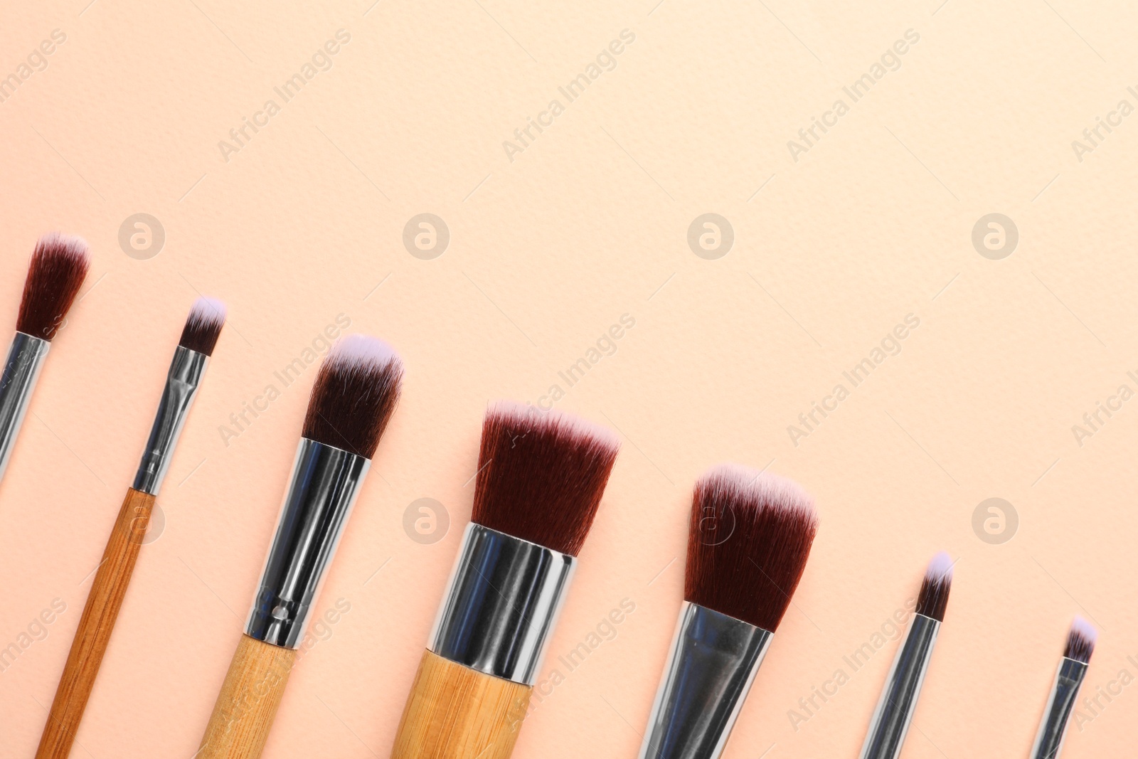 Photo of Set of makeup brushes on beige background, flat lay. Space for text