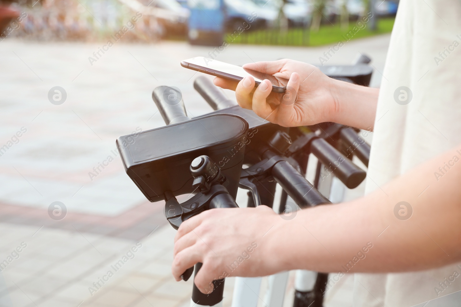 Photo of Man using smartphone to pay and unblock electric kick scooter outdoors, closeup