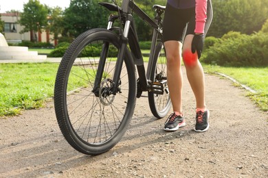 Image of Woman with injured knee and bicycle outdoors, closeup