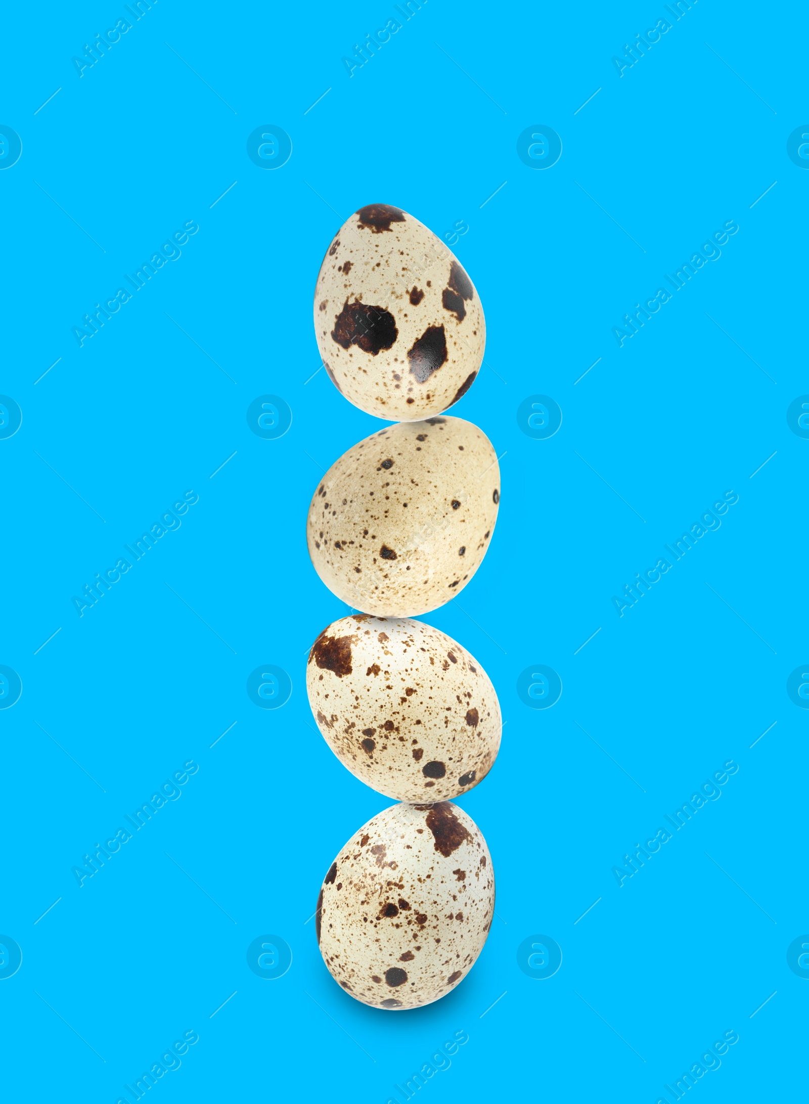 Image of Stacked speckled quail eggs on light blue background