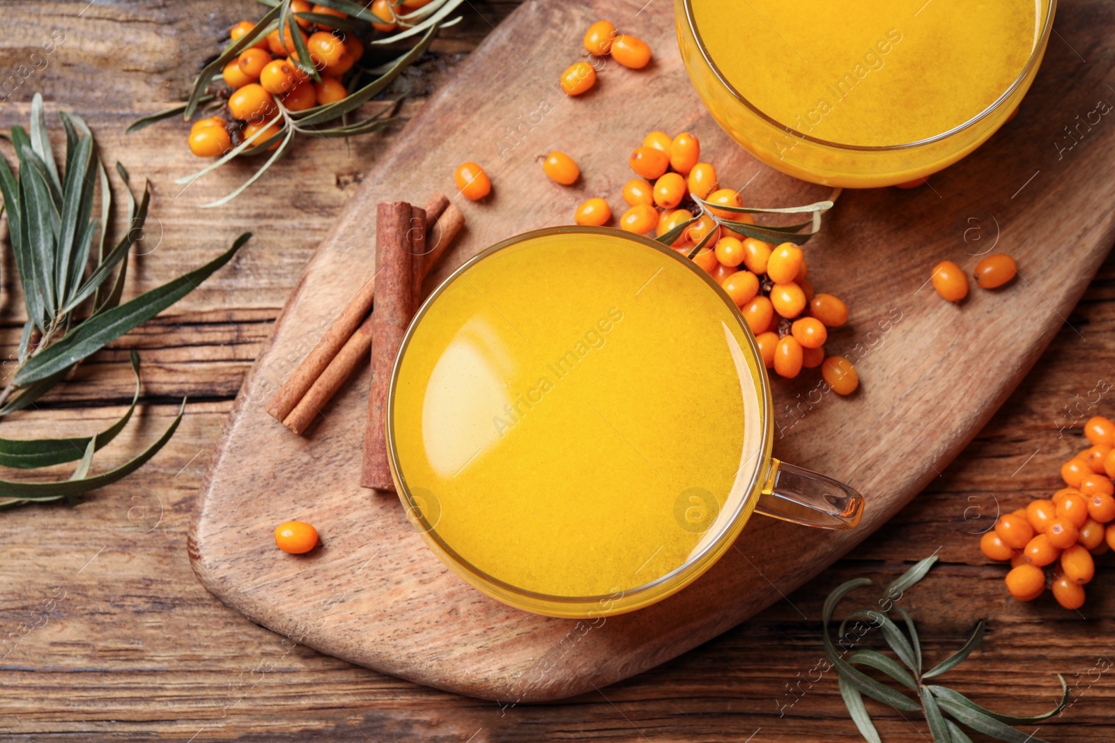 Photo of Sea buckthorn tea and fresh berries on wooden table, flat lay