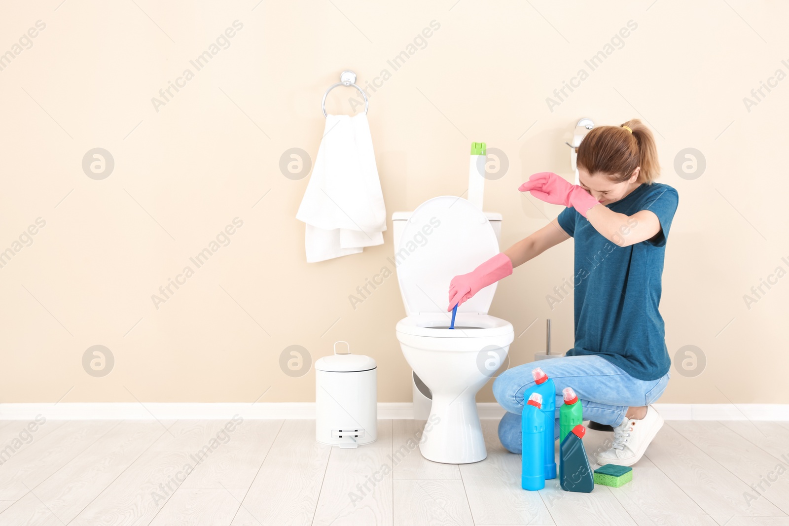 Photo of Woman cleaning toilet bowl in bathroom