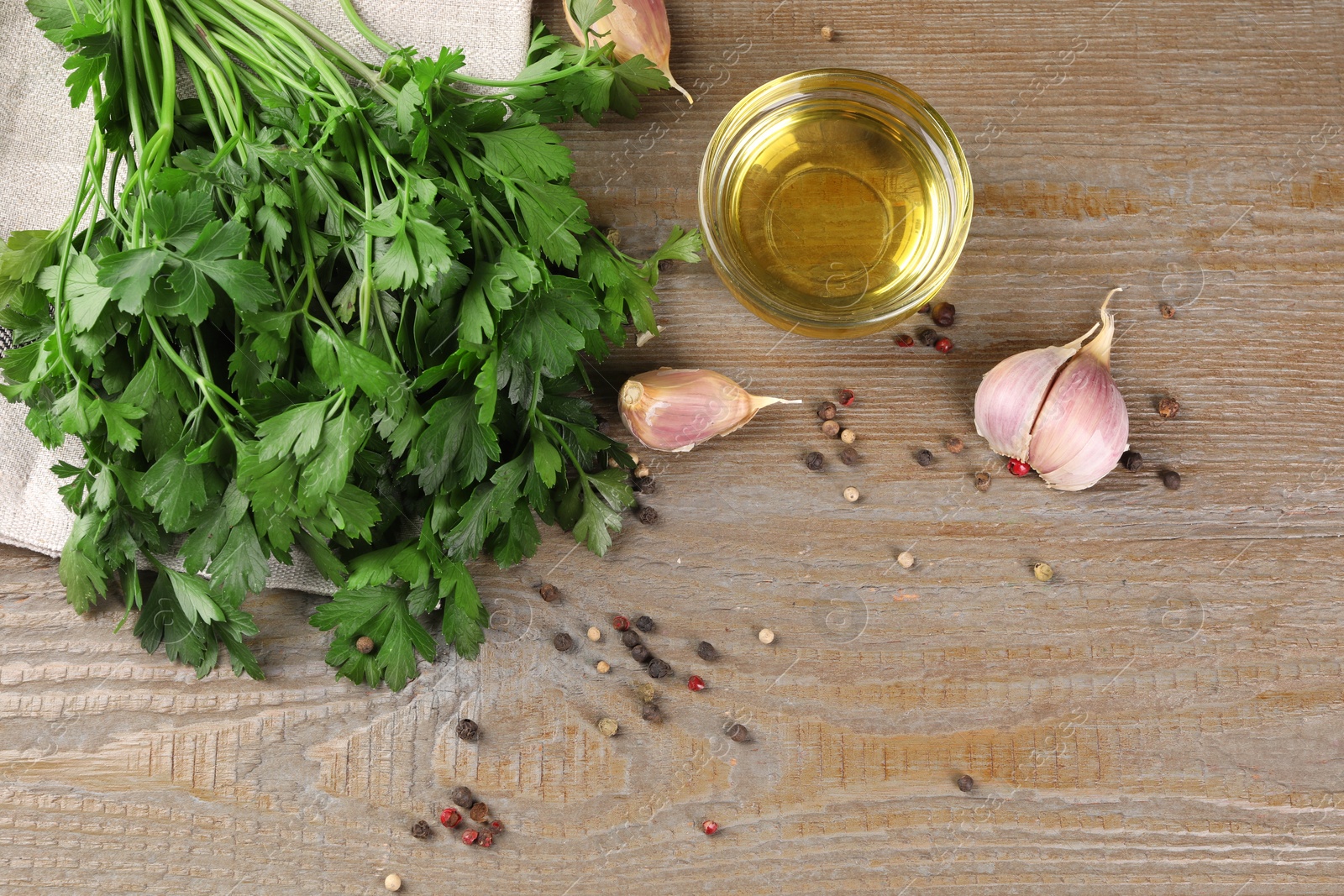 Photo of Bunch of raw parsley, oil, garlic and peppercorns on wooden table, flat lay