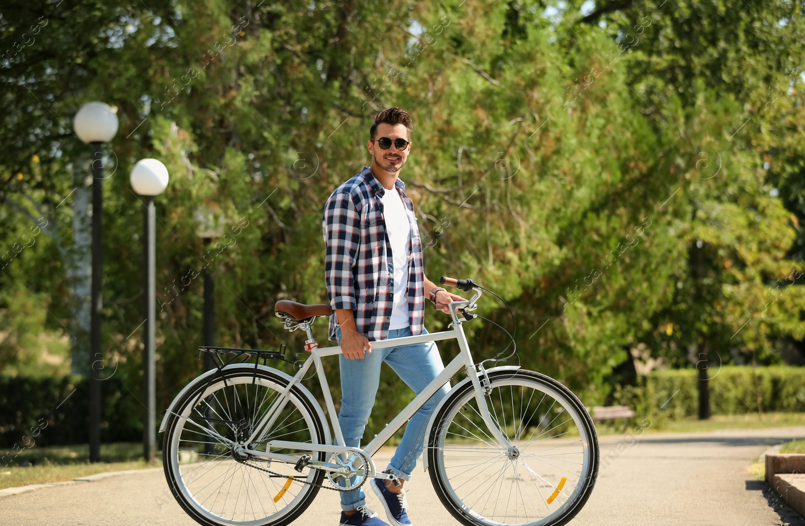 Photo of Handsome young hipster man with bicycle in park