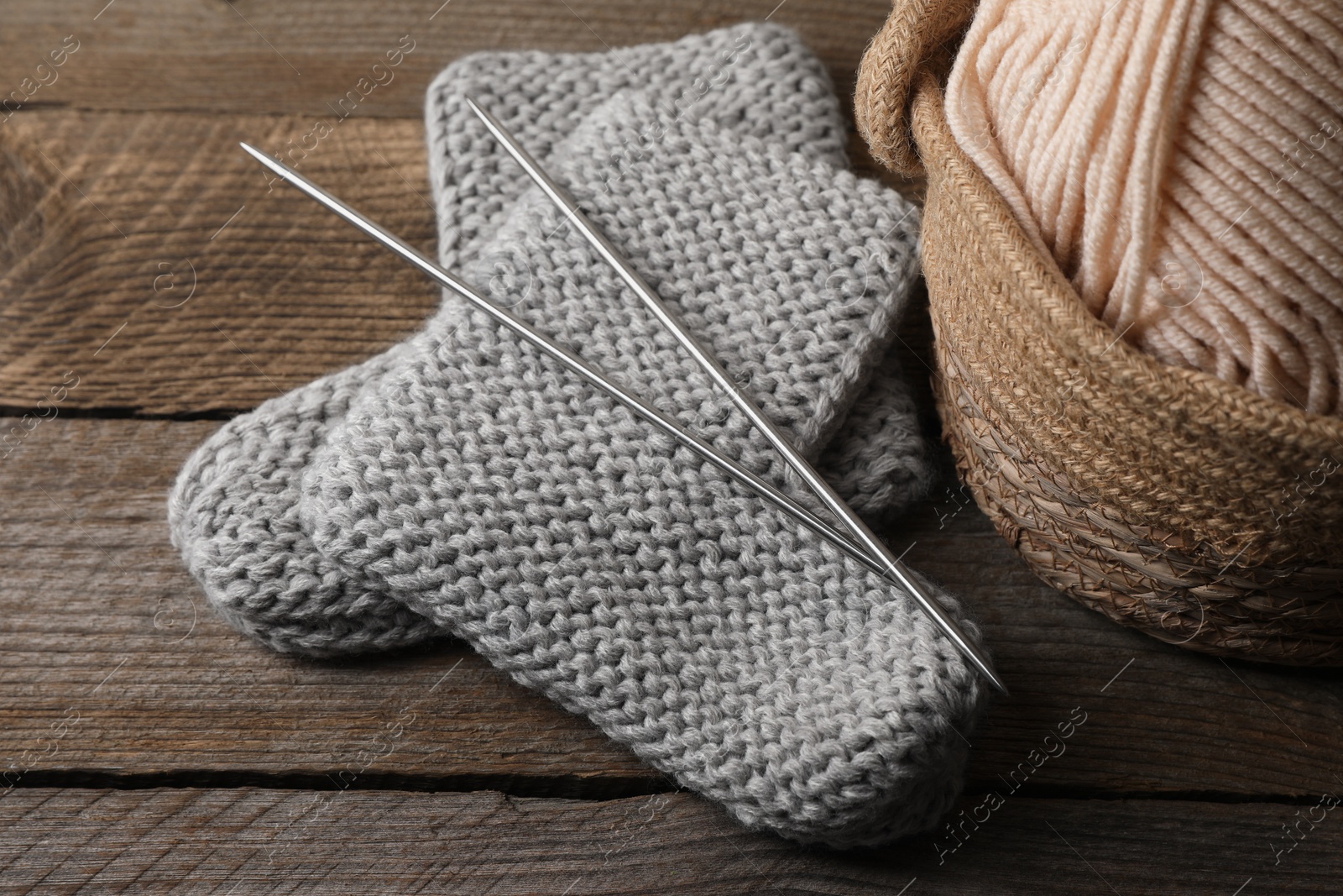 Photo of Soft colorful yarns, knitted socks and metal needles on wooden table