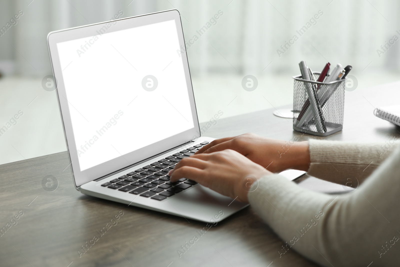 Photo of Woman using laptop at wooden desk indoors, closeup