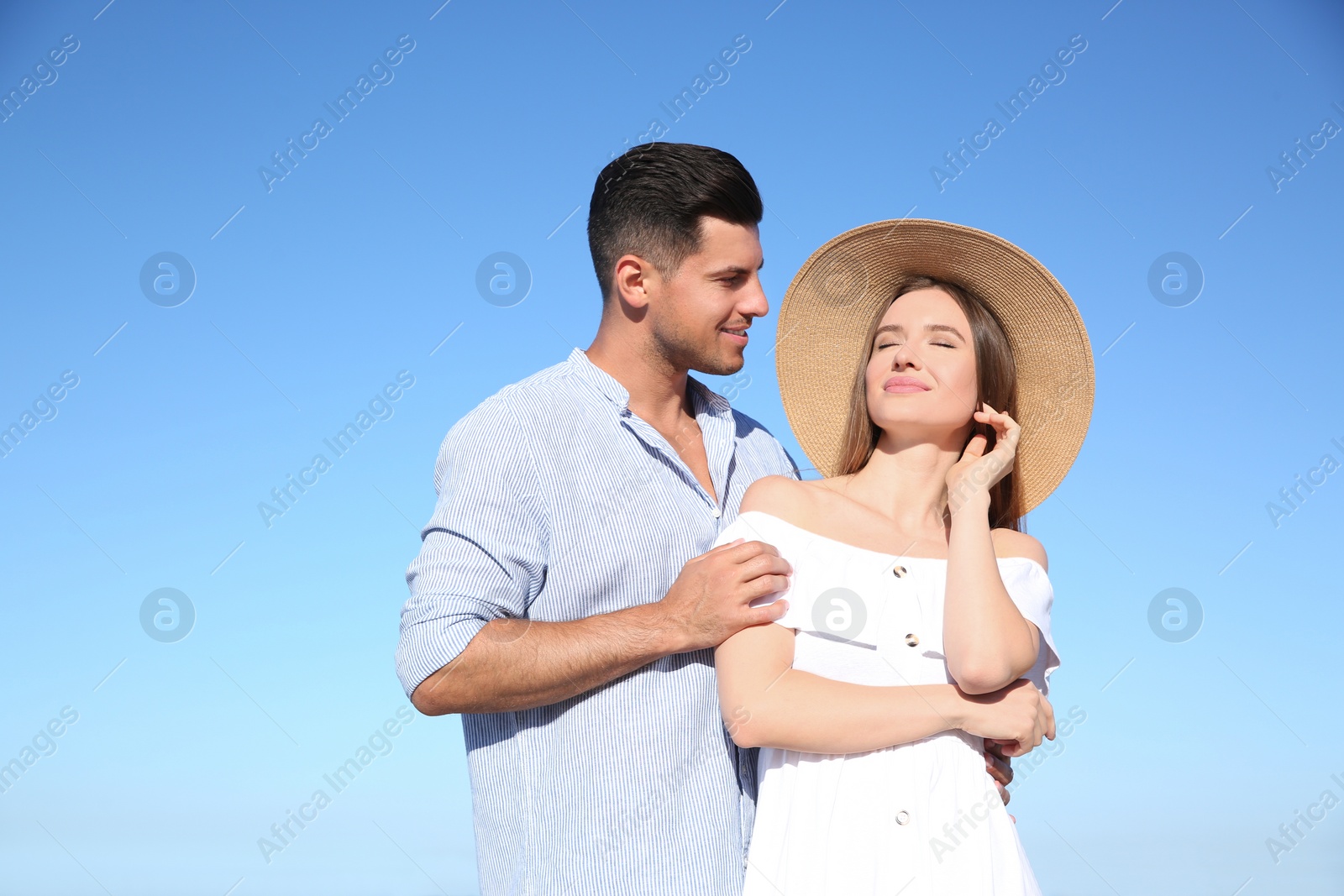 Photo of Lovely couple against blue sky outdoors. Summer vacation