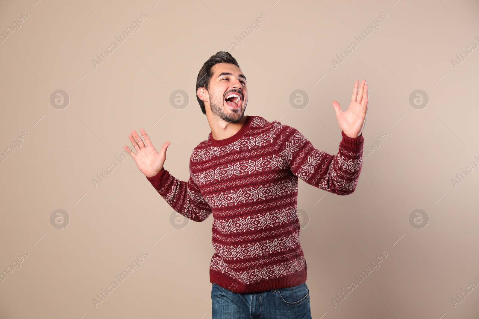 Photo of Happy young man in Christmas sweater on beige background