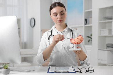 Photo of Gastroenterologist showing human stomach model at table in clinic