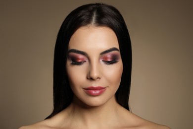 Photo of Beautiful young woman with evening makeup on brown background. Eye shadow product