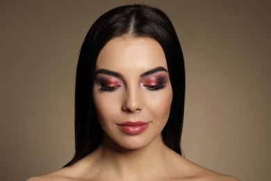 Beautiful young woman with evening makeup on brown background. Eye shadow product